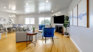 A modern living room with a fireplace, a television, and a dining area with a table and chairs.