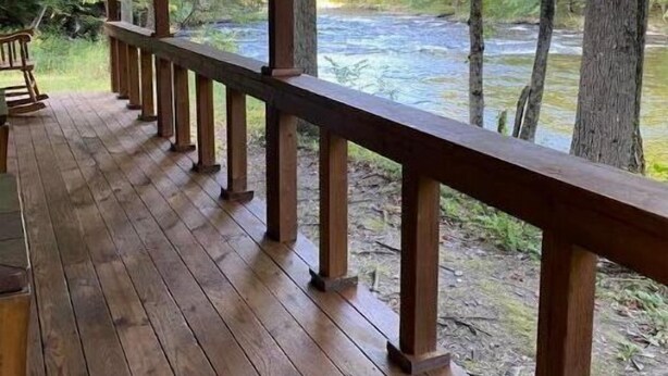 Een houten terras met een hekwerk, met uitzicht op een rivier.