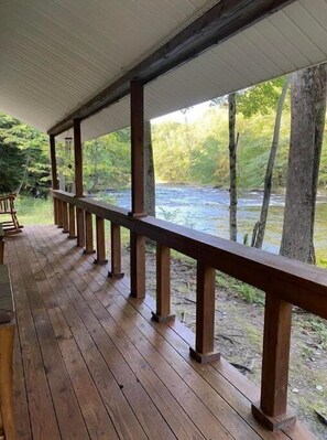 A wooden deck with a railing overlooking a river. - Riverside cabin, fly-fish for trout or just relax! (Malone)