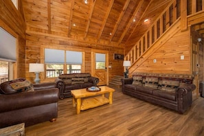 Relax in this cozy cabin-style living area with a high ceiling, leather sofas, and a wooden coffee table.