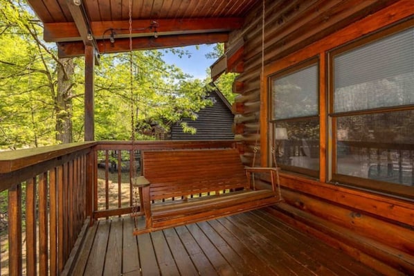 Sit on the porch and enjoy the peaceful surroundings from the comfort of a cozy cabin with a bench and swing.