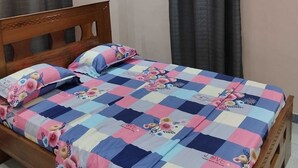 Une chambre à coucher avec un lit en bois, une couvre-lit à carreaux et un ventilateur de plafond.