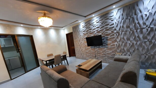 Un salon moderne avec un canapé, une table basse et un téléviseur fixé à un mur à texture.