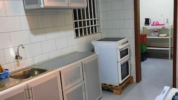 Een koelkast, een oven, een kookplaat, kookgerei, borden en bestek