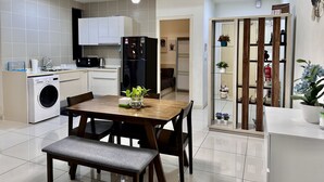 A modern kitchen with a dining area, a washing machine, and a refrigerator. - Homey Family Gateway (Petaling Jaya)