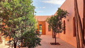 An outdoor courtyard with a paved floor, surrounded by walls with arched windows and doorways. - Luxurious Villa Beldi Chic 20 minutes from Marrakech Medina (Tamesloht)