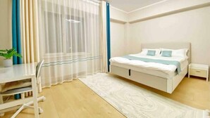 A bedroom with a bed, bedside table, and a desk with a chair.
