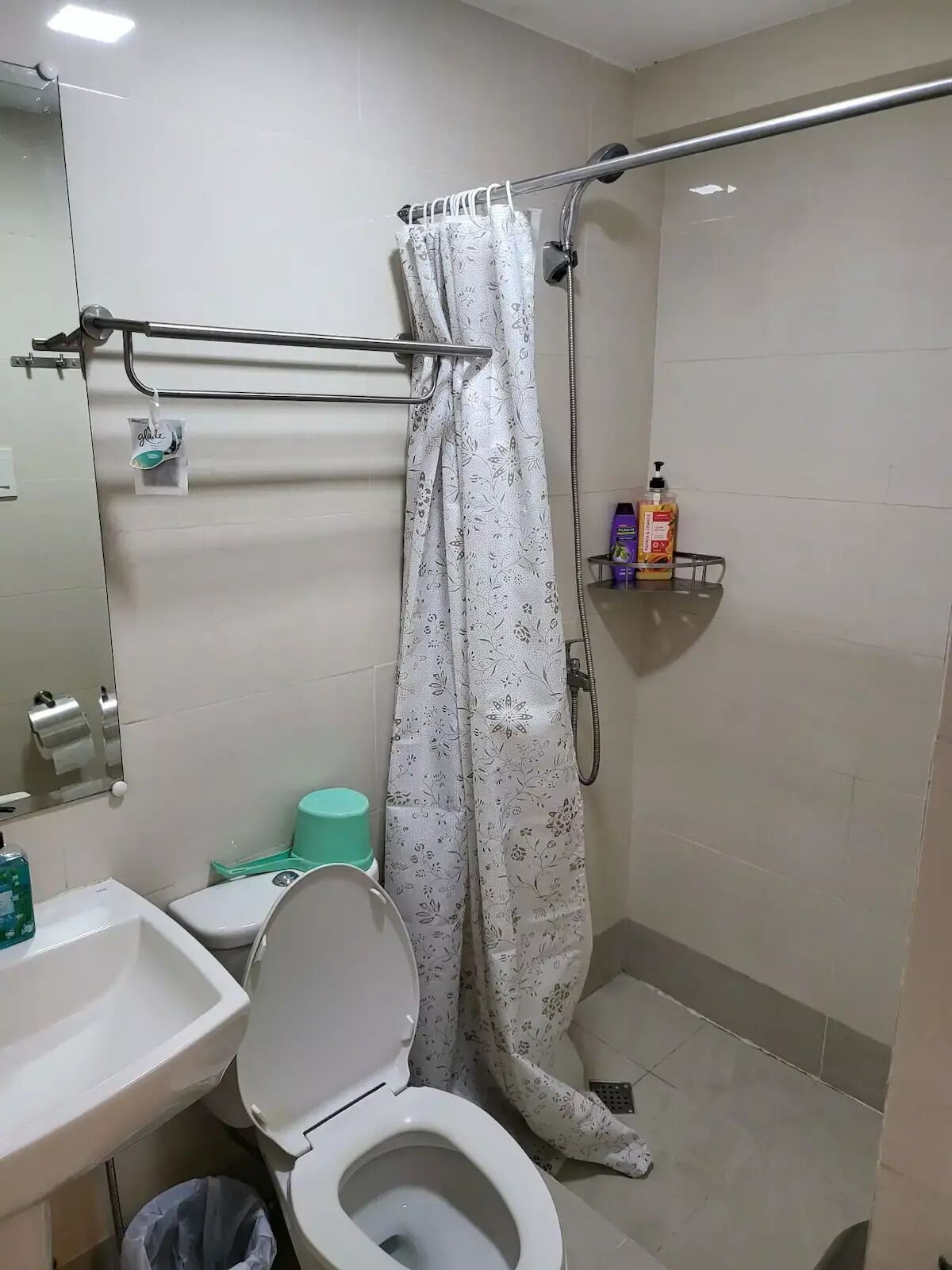 A bathroom with a toilet, sink, shower, and a towel rack.