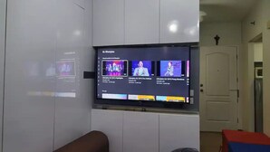 Un téléviseur fixé au mur diffuse une émission intitulée « Style de vie ».