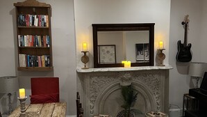 A living room with a fireplace, a bookshelf, a dining table, and a piano. - Townhouse in Old Fishtown! 10 mins to Center City & Stadiums (Philadelphia)
