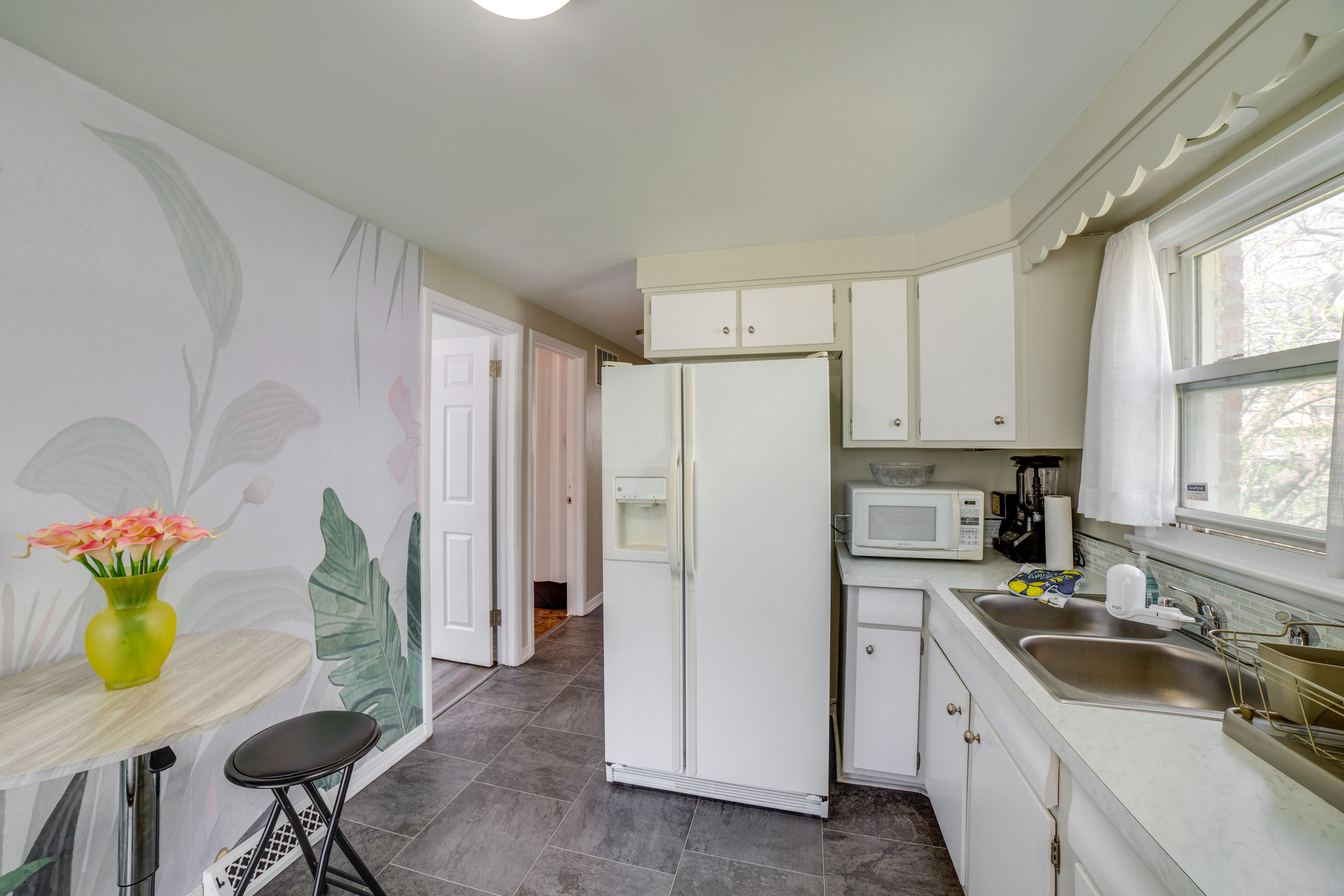 A compact kitchen with white cabinets, a refrigerator, a microwave, and a sink.
