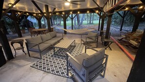 An outdoor covered patio with a sofa, chairs, a table, and a hammock. - "MUCK IT"-QUINTESSENTIAL Edisto Beach House w/in Steps of Beach (Edisto Island)
