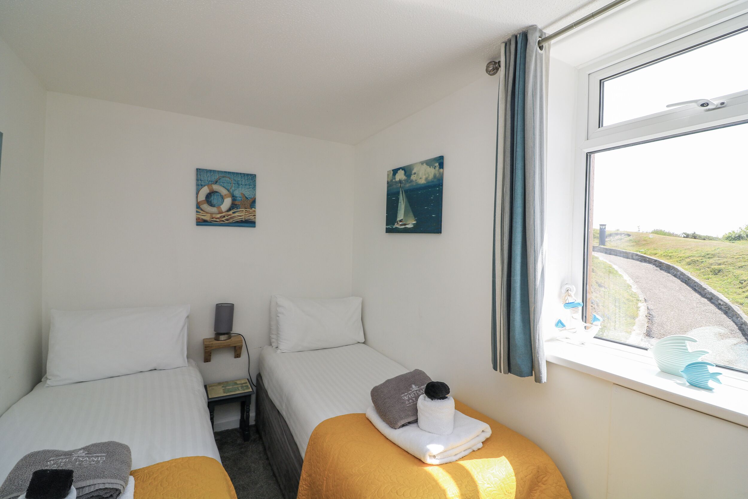 Une chambre d’hôtel avec deux lits, une fenêtre donnant sur une rue et des œuvres d’art accrochées aux murs.