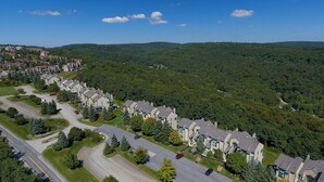 A residential area with modern houses, a main road, and a forested hill in the background. - Seven Springs 2 BR Deluxe Condo with Mountain Views by RedAwning (Champion)
