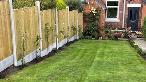 A well-maintained lawn with a wooden fence, a brick house, and a variety of potted plants. - Commuters Getaway Chesterfield (Chesterfield)