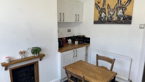 A kitchen with white cabinets, a wooden table, and a painting of donkeys on the wall. - Commuters Getaway Chesterfield (Chesterfield)