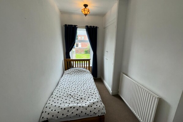 A narrow room with a single bed, a radiator, and a window with curtains. - Commuters Getaway Chesterfield (Chesterfield)