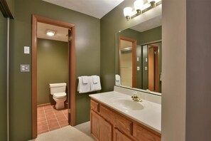 A bathroom with a white toilet, a sink, and a mirror. - Seven Springs Sunridge 3 BR Condo, Sleeps 10! by RedAwning (Champion)