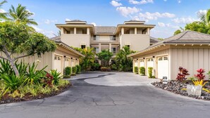 A two-story hotel with a central courtyard, featuring a curved driveway and tropical landscaping.