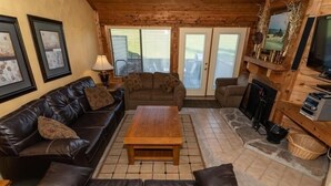 A cozy living room with a leather couch, a wooden coffee table, and a fireplace.