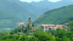Un village dont l’église, avec son clocher imposant, domine les environs, entouré de collines verdoyantes et sous un ciel dégagé.