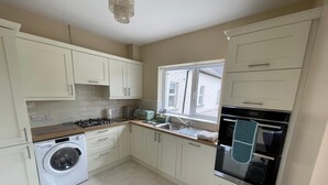 A compact kitchen with a washing machine, a stove, a sink, and an oven. - Beautiful Irish Farmhouse an Hours Drive From Four Irish Cities (Clonmel)