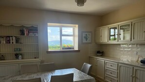 A kitchen with a dining table, chairs, and a window with a view of greenery. - Beautiful Irish Farmhouse an Hours Drive From Four Irish Cities (Clonmel)