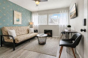 Un salon comprenant un canapé, une table basse, une cheminée et un téléviseur fixé au mur.