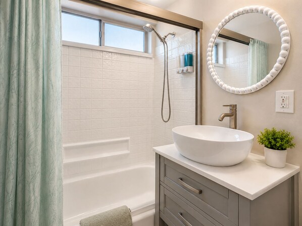 Un baño con bañera, lavamanos con espejo y ducha.