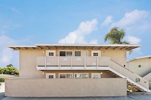 A two-story building with a flat roof, balconies, and a staircase leading to the upper floor. - Sunny Nearly Beachfront Upper Loft 38 (Ventura)