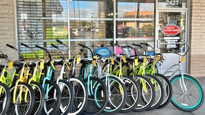 Een rij fietsen geparkeerd voor een winkel met een groot raam en een bord waarop 'Matt's Cycling Center' staat.