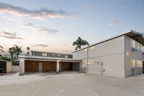 A modern building with a flat roof, multiple garage doors, and a concrete driveway. - Beach Loft 32 Steps From the Sand (Ventura)