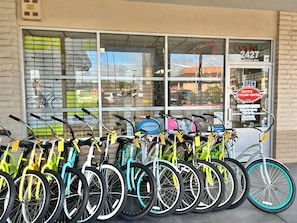 A row of bicycles parked outside a store with a large window and a sign indicating 'Matt's Cycling Center'.