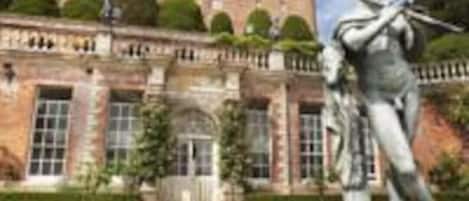 Un bâtiment qui ressemble à un château, avec une statue devant.