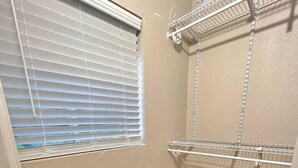 Una habitación pequeña y bien iluminada, con un banco de madera, un espejo y estantes metálicos.
