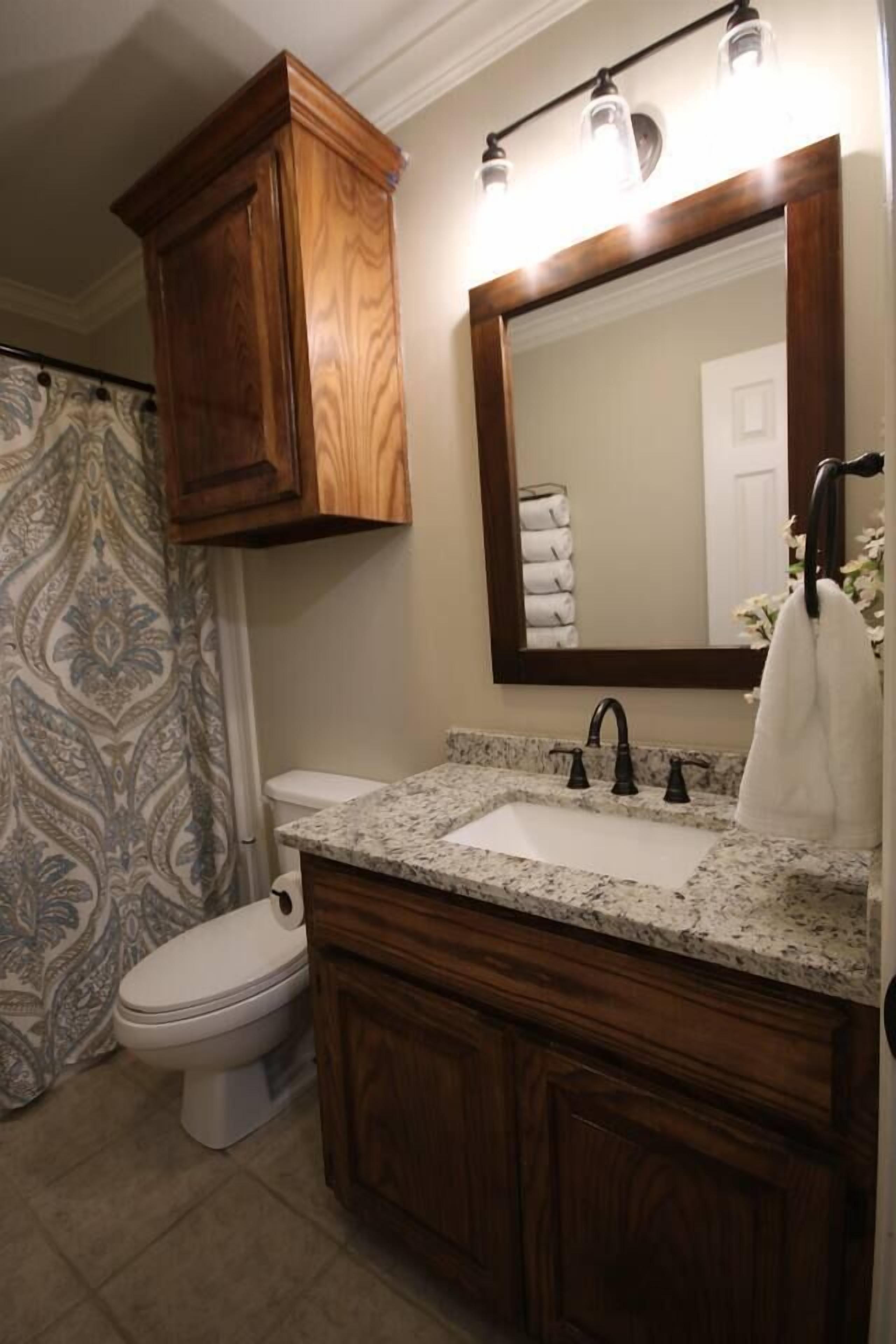 A bathroom with a wooden vanity, a sink, a mirror, and a shower curtain.