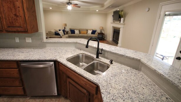 A kitchen with granite countertops, a double sink, and wooden cabinets. - Royal Entertainer - STAYeasttexas (Chandler)
