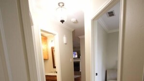 A hallway with wooden flooring leading to a kitchen area with cabinets and a countertop. - Royal Entertainer - STAYeasttexas (Chandler)