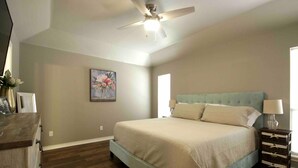 Une chambre à coucher avec un lit, un ventilateur de plafond, une commode et une table de chevet.