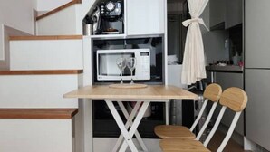 Une cuisine compacte équipée d’un four à micro-ondes, d’une machine à café et d’une petite table avec deux chaises.