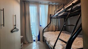Een slaapkamer met stapelbed, een garderobe, een kledingroede en een raam met gordijnen.