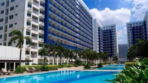 A hotel with a large swimming pool, palm trees, and modern architecture. - Sea Resi.MoA.Airport Netflix (Pasay)