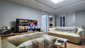 A living room with a large flat-screen TV, a sofa, a coffee table, and a staircase leading to another level. - Daejeon Bedroom 3, Bathroom 2, Spacious Living Room Free Parking (Pasay)