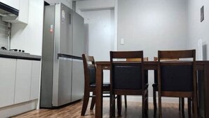 A compact kitchen with a refrigerator, wooden dining table, and chairs. - Daejeon Bedroom 3, Bathroom 2, Spacious Living Room Free Parking (Pasay)