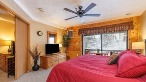 A bedroom with a bed, a ceiling fan, a TV, a desk, and a window with a view of trees. - Seven Springs Stoneridge 3 BR Condo, Private Deck by RedAwning (Champion)