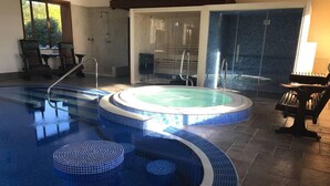 Una piscina con una vasca idromassaggio, un lettino prendisole e vista sull'esterno.