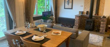 A cozy living room with a fireplace, a dining area with a table set for two, and a comfortable seating arrangement.