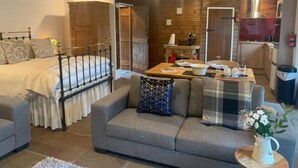 Una camera accogliente con un letto, un divano, un tavolo da pranzo e un angolo cottura.