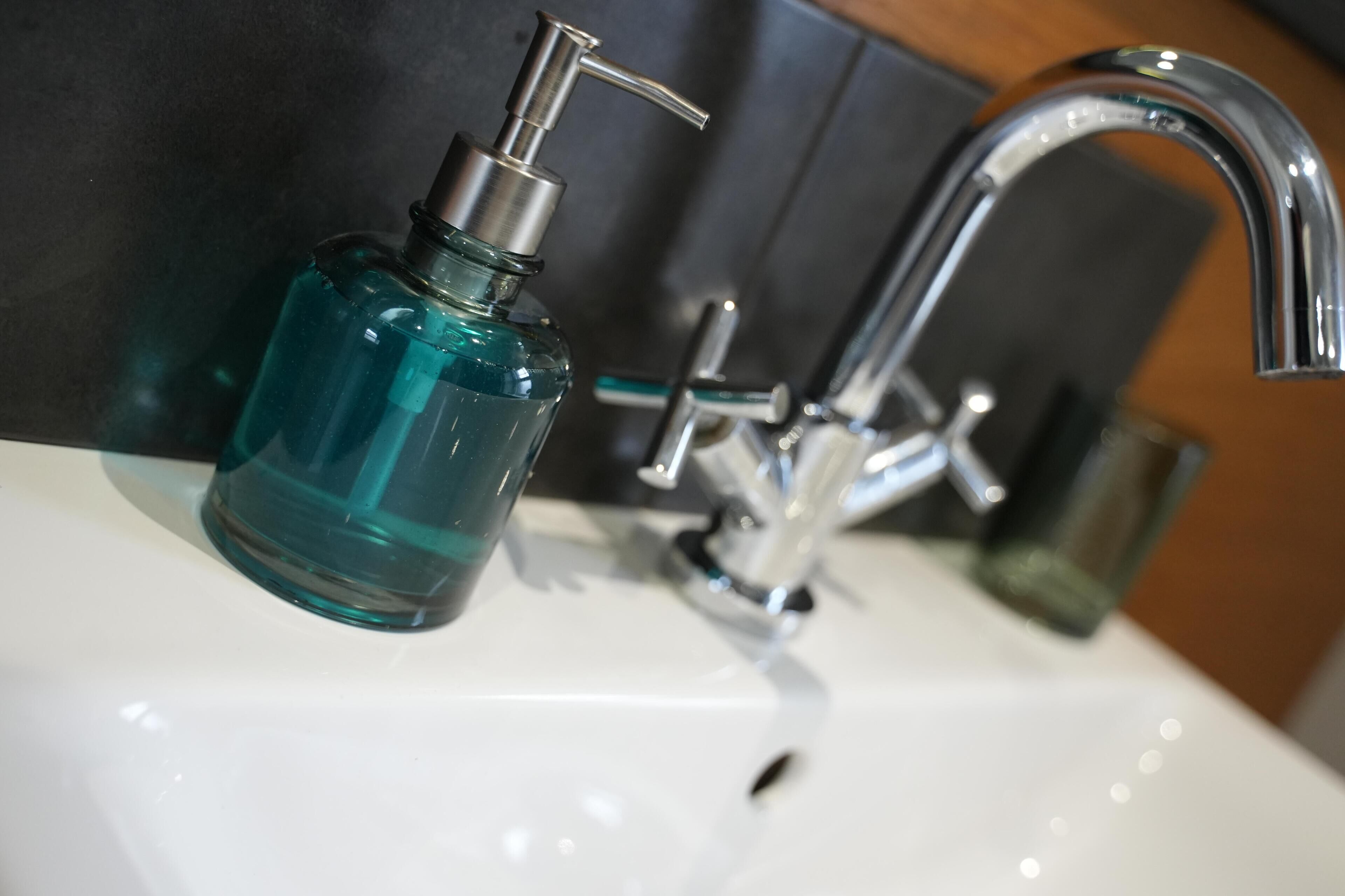 A bathroom sink with a chrome faucet and a blue soap dispenser.