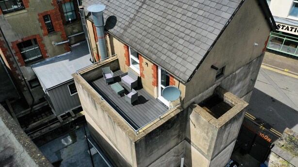 A multi-story building with a rooftop terrace featuring outdoor furniture and satellite dishes. - Charming 1-bed & Balcony Flat in Merthyr Tydfil (Merthyr Tydfil)